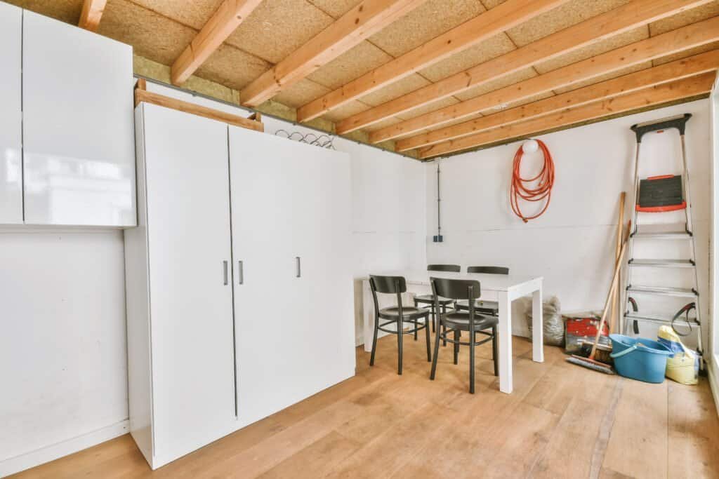 Organized garage with storage cabinets, table, and tools by Struxure 28 Builders.