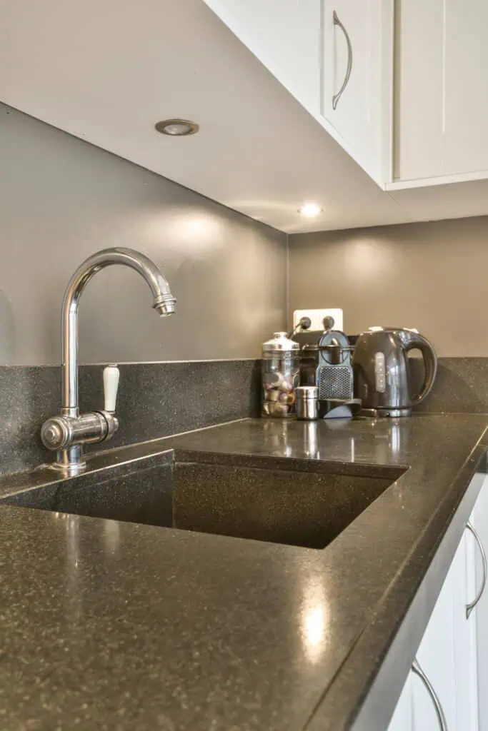 Contemporary kitchen with black countertop, stainless steel faucet, and small appliances.