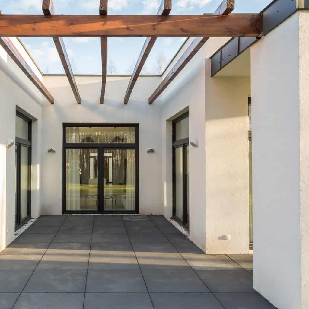 Contemporary patio with glass doors and wooden pergola.