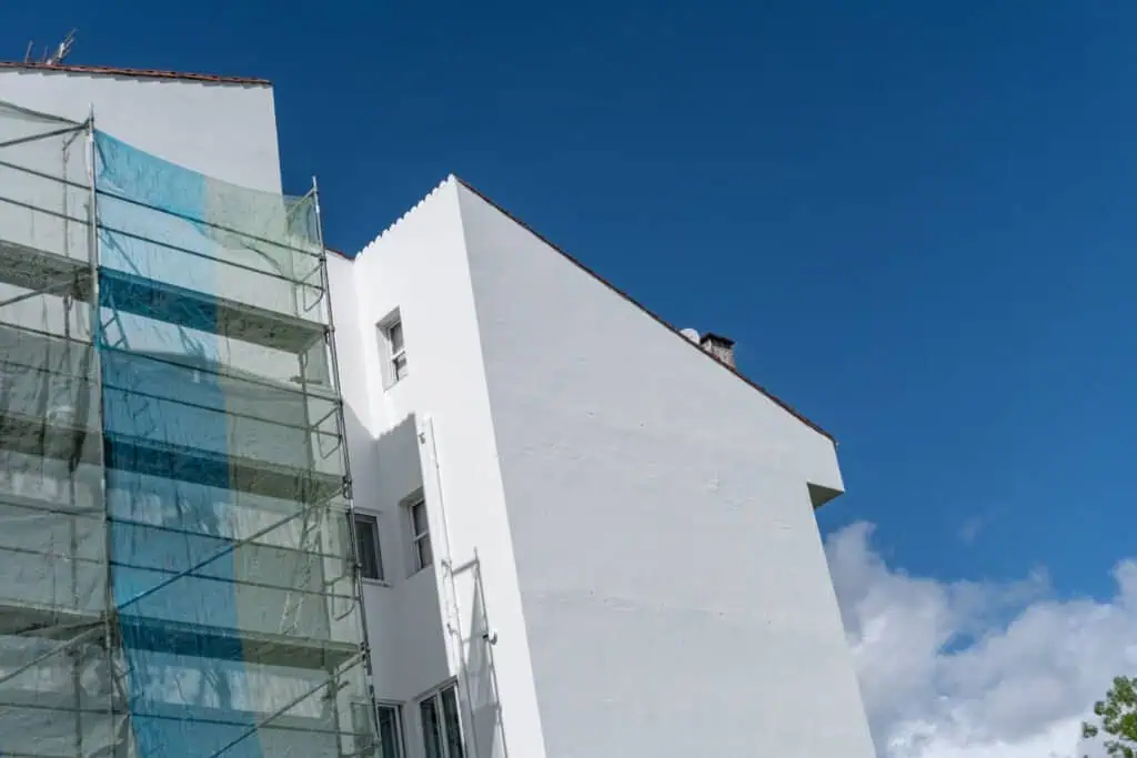 Contemporary white building with scaffolding against a blue sky.