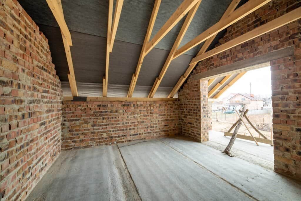 Construction site with brick walls and wooden roof framing.